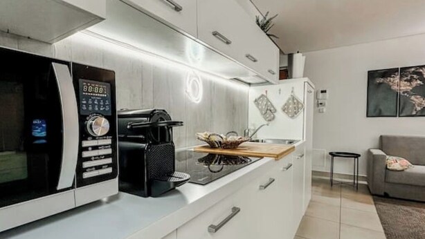 Una cocina moderna con microondas integrado, cafetera y tabla de cortar de madera.