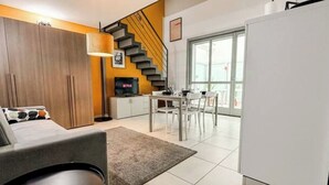 A modern living room with a sofa, a dining table, and a staircase. - Loft Design + Garage and Fitness Area (Torino)