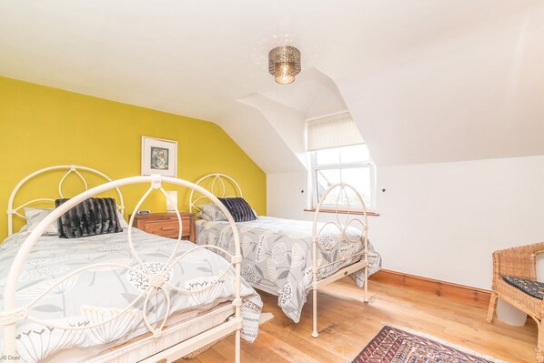 A bedroom with two beds, a window, and a ceiling light fixture.