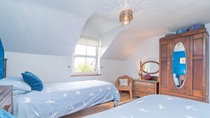 A bedroom with two beds, a dresser, a mirror, and a window.