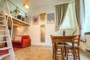 Una sala moderna con un sofá rojo, una mesa de comedor de madera y una escalera.