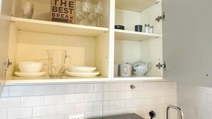 A kitchen with white cabinets, a tiled backsplash, and a sign that reads "THE BEST BREAKFAST."