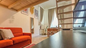 A modern living room with a sofa, a dining table, and a TV.