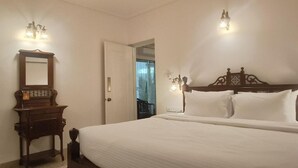 A bedroom with a large bed, a wooden dresser, and two wall sconces. - Cozy 1BR Apt in Siolim 3km to Uddo Beach (Siolim)