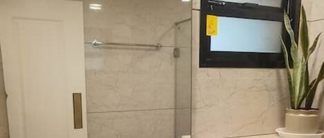 A bathroom with a sink, mirror, toilet, and a potted plant.