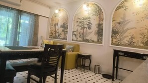 A room with a dining table, chairs, a sofa, and a small side table. - Cozy 1BR Apt in Siolim 3km to Uddo Beach (Siolim)
