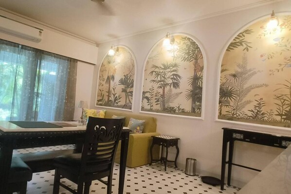 Una habitación con una mesa de comedor, sillas, un sofá y una mesita auxiliar.