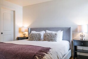 Una camera da letto ordinata con un letto, due comodini e una porta.
