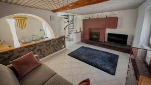 A living room with a fireplace, a sofa, and a staircase leading to an upper floor. - Royal Palace Suite in Piazza Castello (Torino)