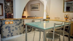 A dining area with a glass table and chairs, a patterned wall, and a wooden counter. - Royal Palace Suite in Piazza Castello (Torino)
