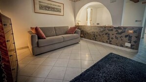 A living room with a sofa, a patterned wall, and a tiled floor. - Royal Palace Suite in Piazza Castello (Torino)