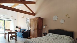 A bedroom with a bed, a wooden wardrobe, a desk with a chair, a sofa, and a window. - Large studio with outdoor jacuzzi  (Lagnes)