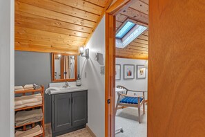 A bathroom with a wooden ceiling, a sink, a mirror, and a shelf with towels. - Modern Mountain Retreat Near Dolly Sods & Skiing 3 Bedroom Home (Davis)