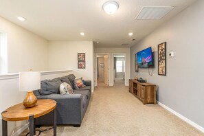 A living room with a grey sofa, a wooden coffee table, and a TV on the wall. - Family-friendly 5br Retreat Splash Pool + Resort Amenities + No Rear Neighbors 5 Bedroom Townhouse (Davenport)