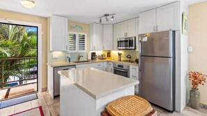 A modern kitchen with white cabinets, stainless steel appliances, and a large island. - Kihei Beach, #210 2 Bedroom Condo (Kihei)