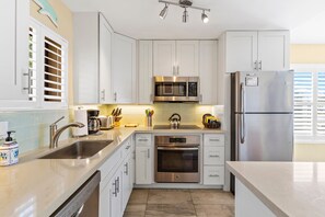 A modern kitchen with white cabinets, stainless steel appliances, and a built-in oven.