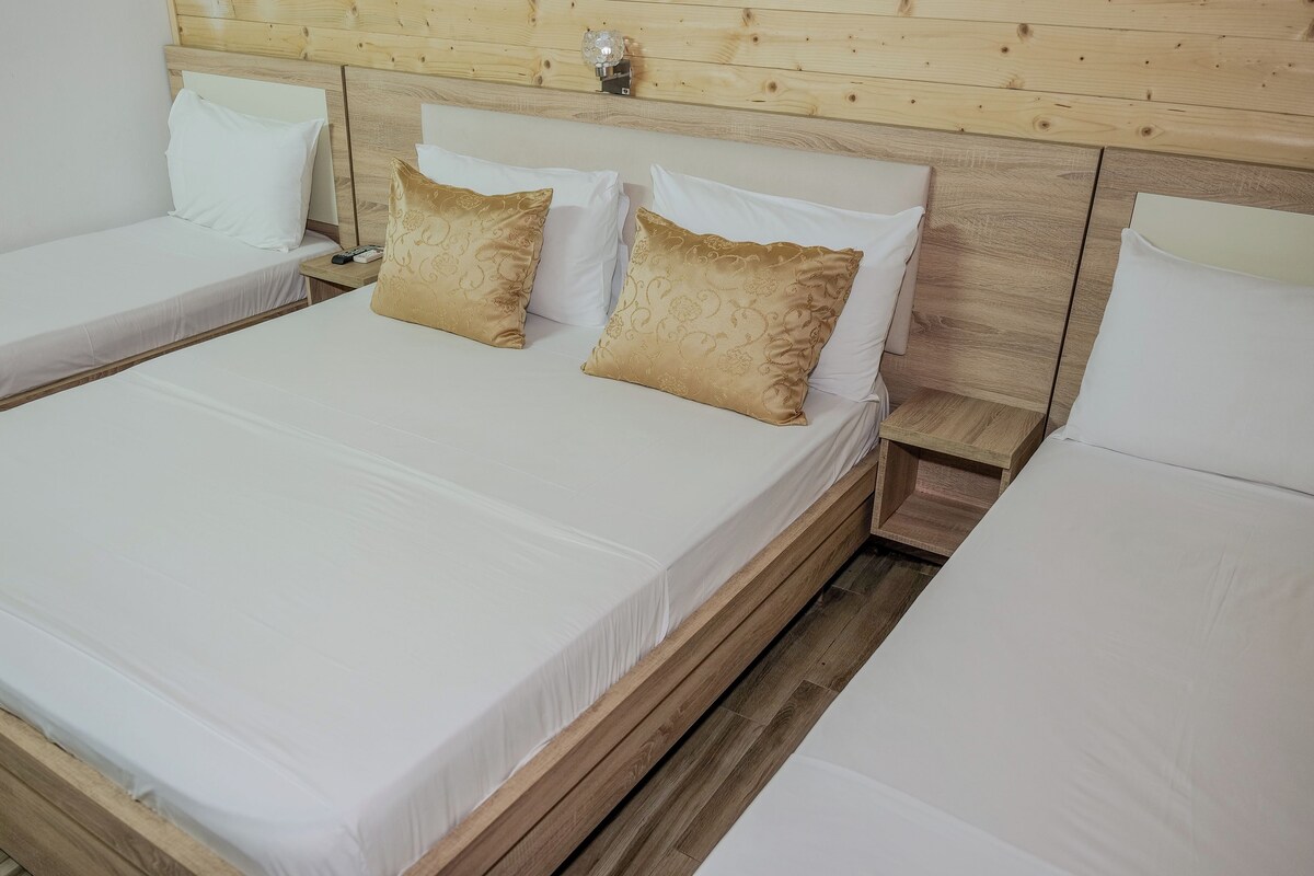 A room with two single beds, each with white linens and a wooden headboard.