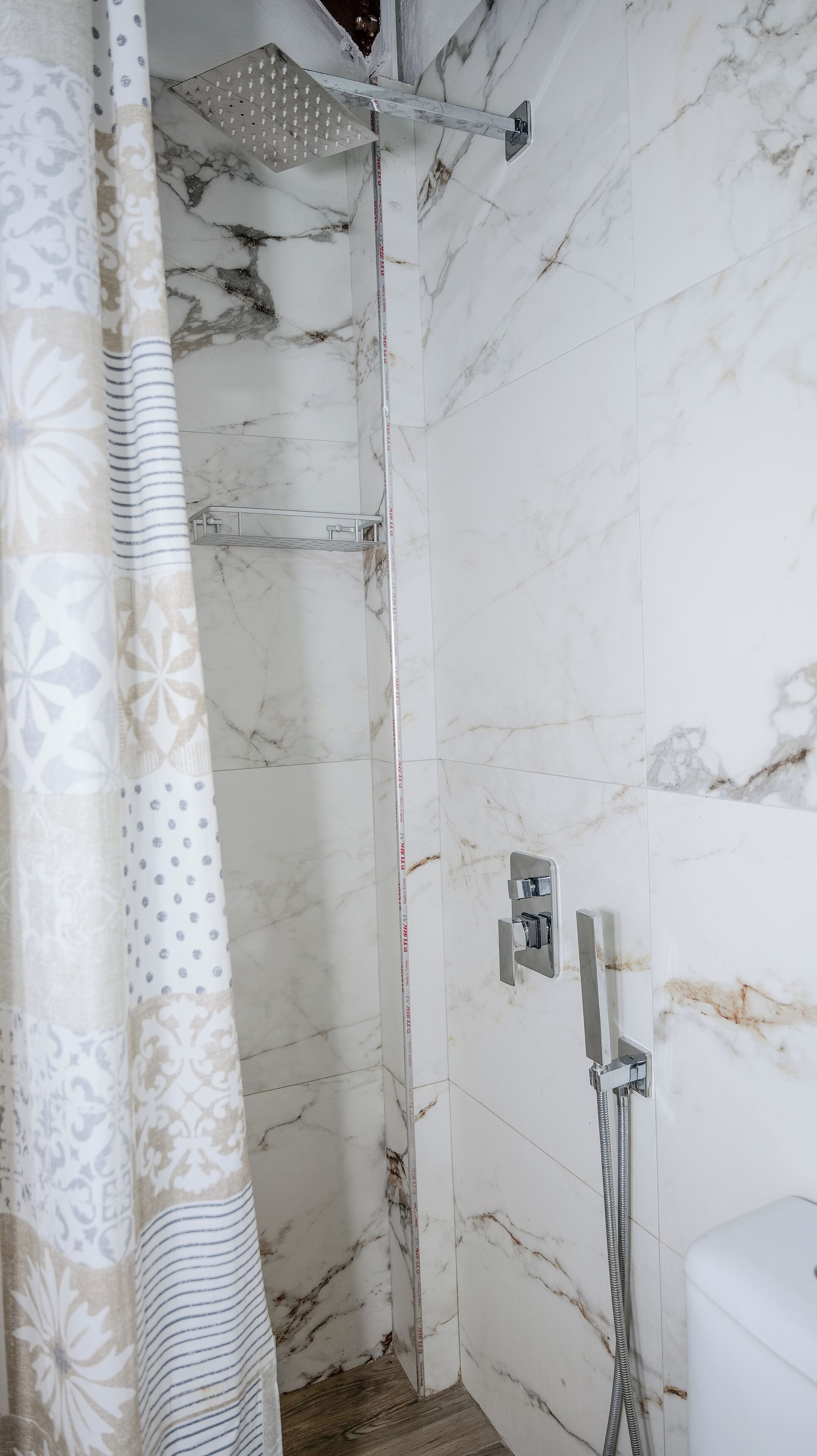 A shower area with a showerhead, a handheld shower attachment, and a handheld shower hose.