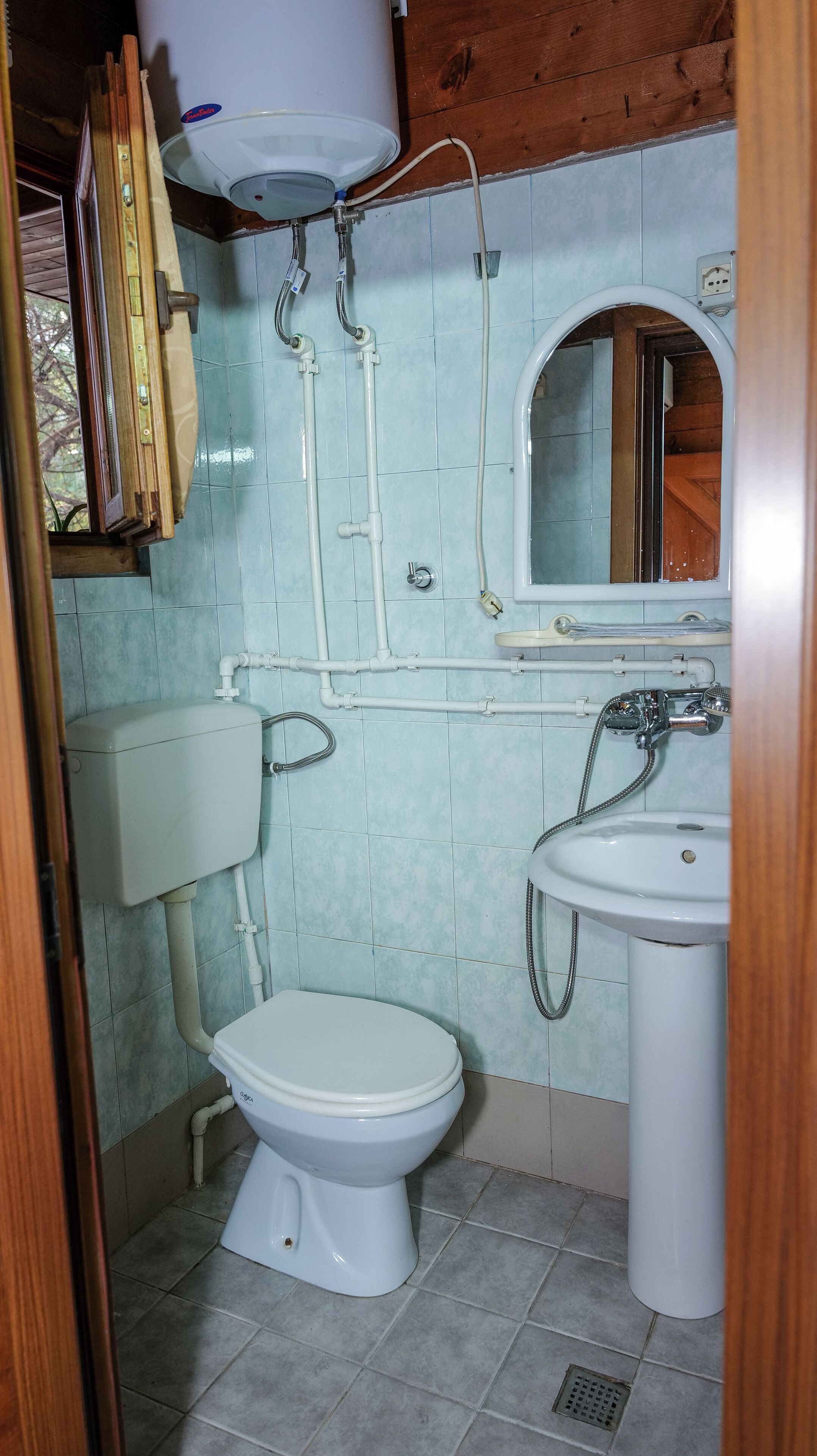 A small bathroom with a toilet, sink, and a water heater mounted on the wall.