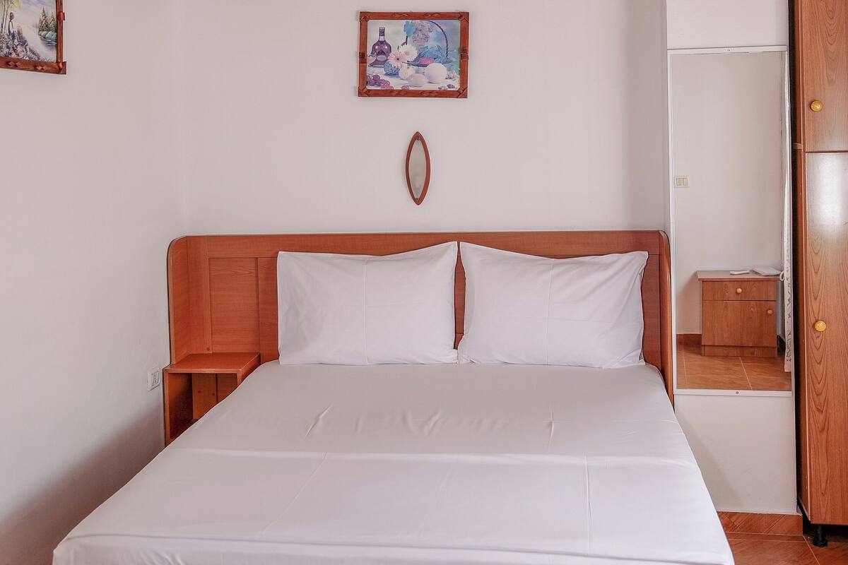 A wooden bed with white bedding in a room with a wooden ceiling and walls.