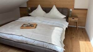 A neatly made bed with a wooden headboard, a bedside table with a lamp, and a tray with mugs on the bed. - ALLGÄUHERZ - Great apartment in Nesselwang - KÖNIGSKARTE (Nesselwang)