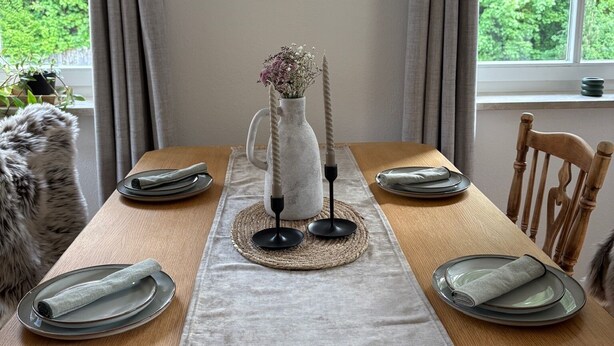 A dining table set with plates, a vase with flowers, and a candle holder. - ALLGÄUHERZ - Great apartment in Nesselwang - KÖNIGSKARTE (Nesselwang)