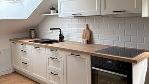 A modern kitchen with white cabinetry, a wooden countertop, a built-in oven, and a skylight above the sink. - ALLGÄUHERZ - Great apartment in Nesselwang - KÖNIGSKARTE (Nesselwang)