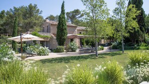 Une maison en pierre dotée d’un patio, entourée d’arbres et d’un jardin bien entretenu.