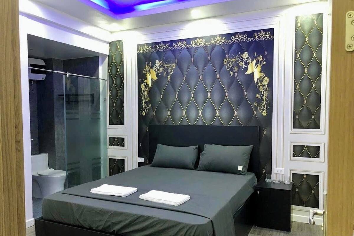 A modern bedroom with a large bed, a glass shower enclosure, and decorative wall panels.
