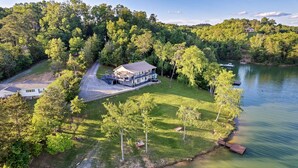 A lakeside property with a large house, a dock, and a boat.