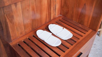 A pair of white slippers on a wooden bench with slatted design.