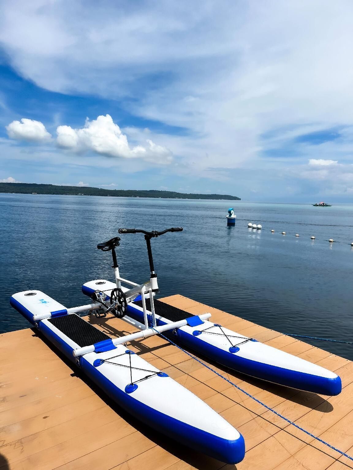 Un barco de plataforma fondeado en una cubierta de madera, con vistas a aguas tranquilas y tierra a lo lejos.