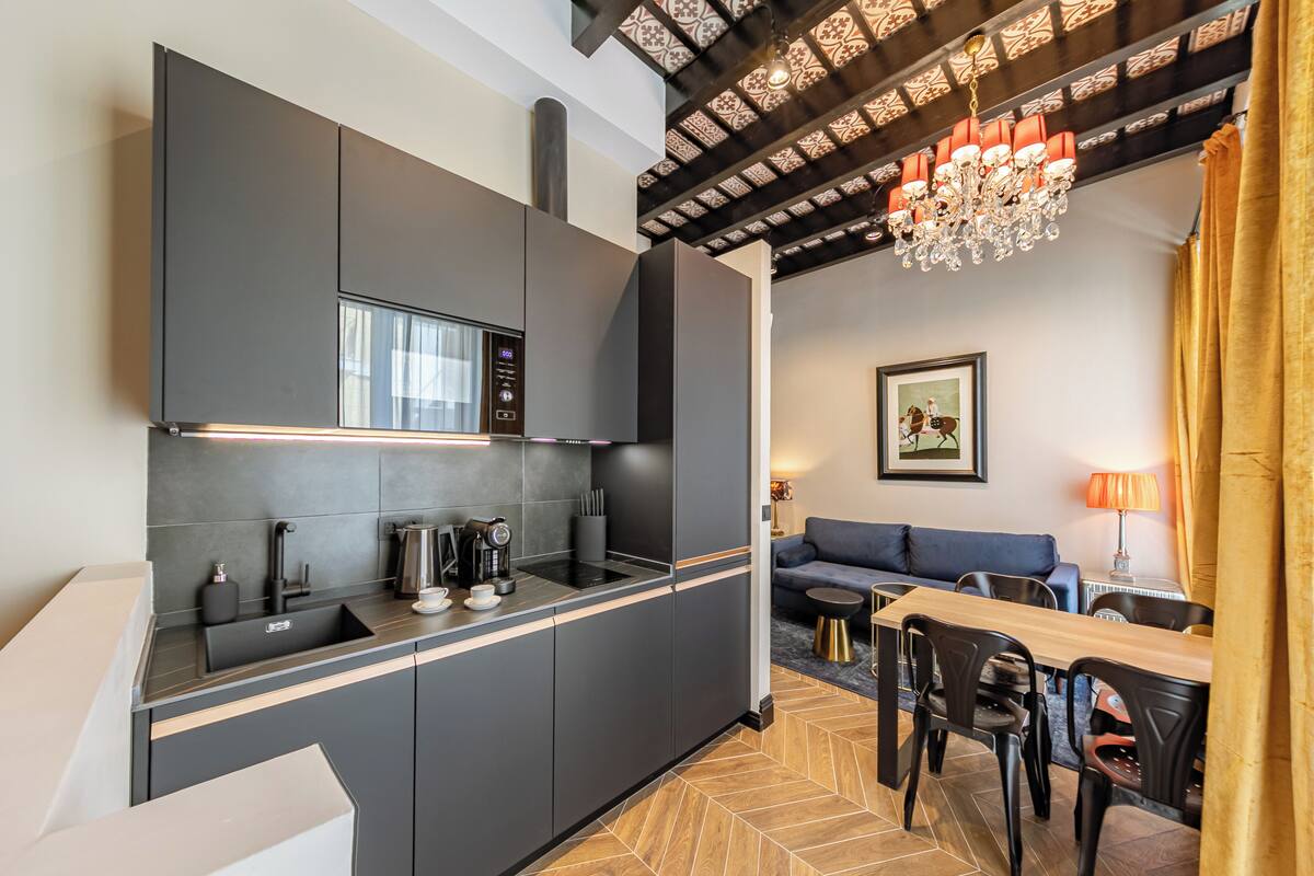 Una cocina moderna con armarios oscuros, microondas integrado y una mesa de comedor de madera con sillas.