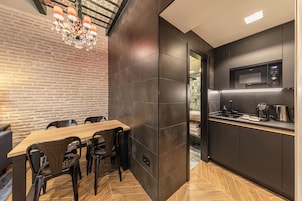 Una cocina moderna con baldosas oscuras, una mesa de comedor de madera y sillas negras.