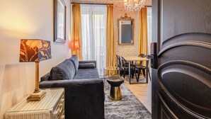 A modern living room with a sofa, a coffee table, and a dining area with chairs and a table. - Casa 1862 Heritage Suites by Stay Unique (Seville)