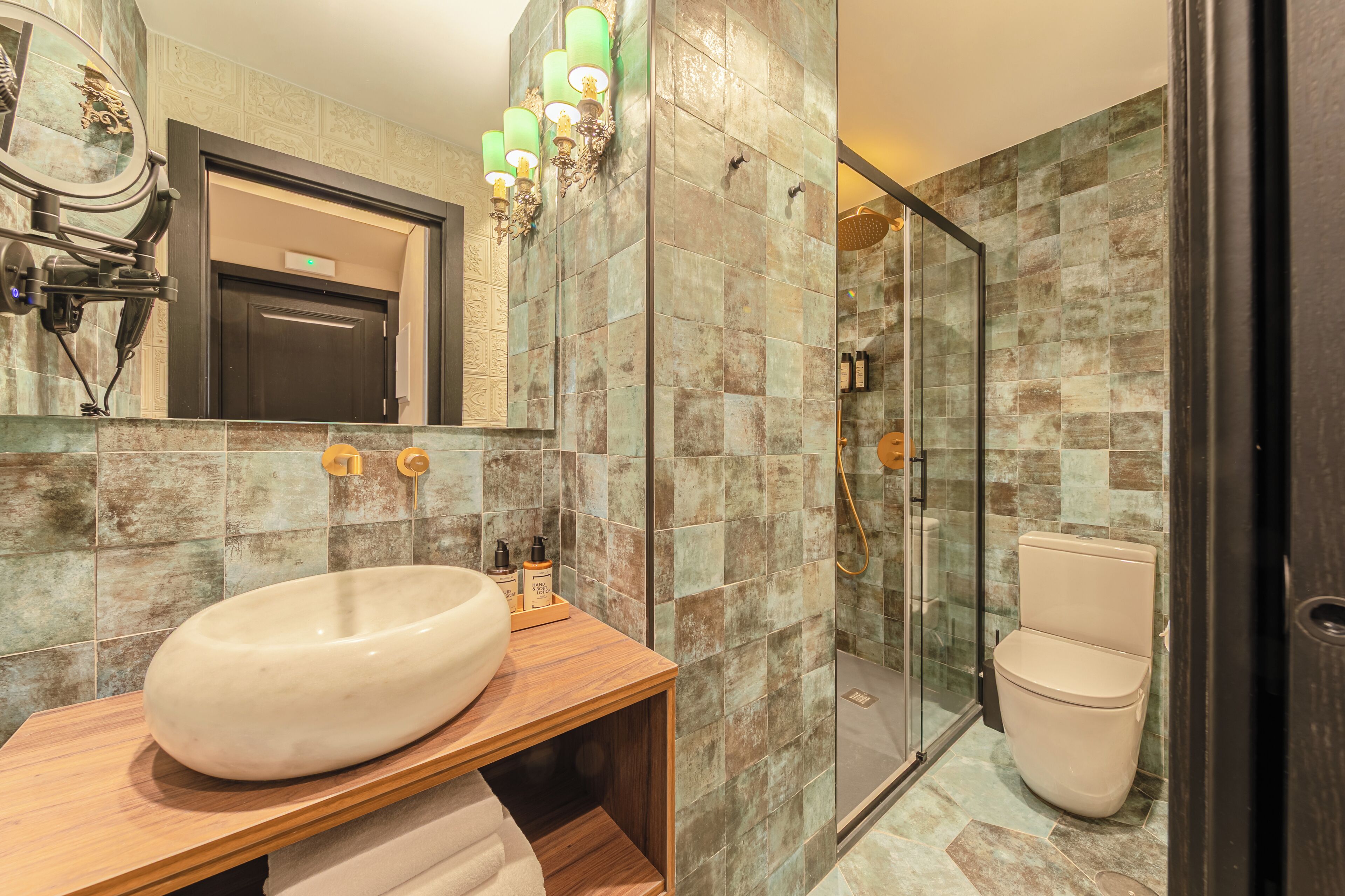 A modern bathroom with a large oval sink, a glass-enclosed shower, and a toilet.