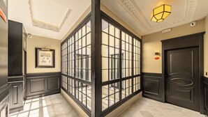 A hallway with a large glass partition, a framed picture on the wall, and a door with a decorative handle. - Casa 1862 Heritage Suites by Stay Unique (Seville)