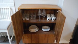 A wooden cabinet with shelves containing glassware and plates. - Apartamentos Altar Suites Conde Luna (León)
