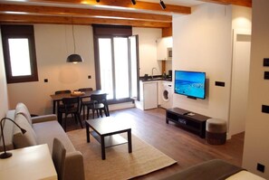 A compact living space with a sofa, dining table, and a TV mounted on the wall. - Altar Suites Caño Badillo by gaiarooms (León)