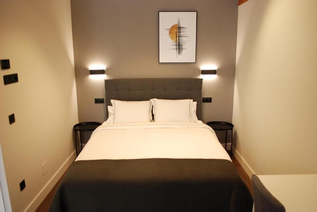 A hotel room with a large bed, two bedside tables, and a wall-mounted artwork.