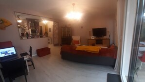 A living room with a sofa, a TV, and a dining area with a table and chairs. - Furnished 3-star house 300 metres from the sea, 84 m², 3 bedrooms (Hyères)