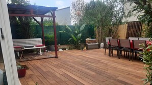 A wooden deck with a pergola, a bench, and a dining area with chairs and a table. - Furnished 3-star house 300 metres from the sea, 84 m², 3 bedrooms (Hyères)