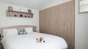 A neatly made bed with white bedding, a wooden headboard, and a small plush toy on the bed. - Mariner's Meadow - Hayling Island (Hayling Island)