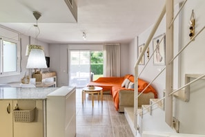 A modern living room with a sofa, a dining area, and a kitchen.