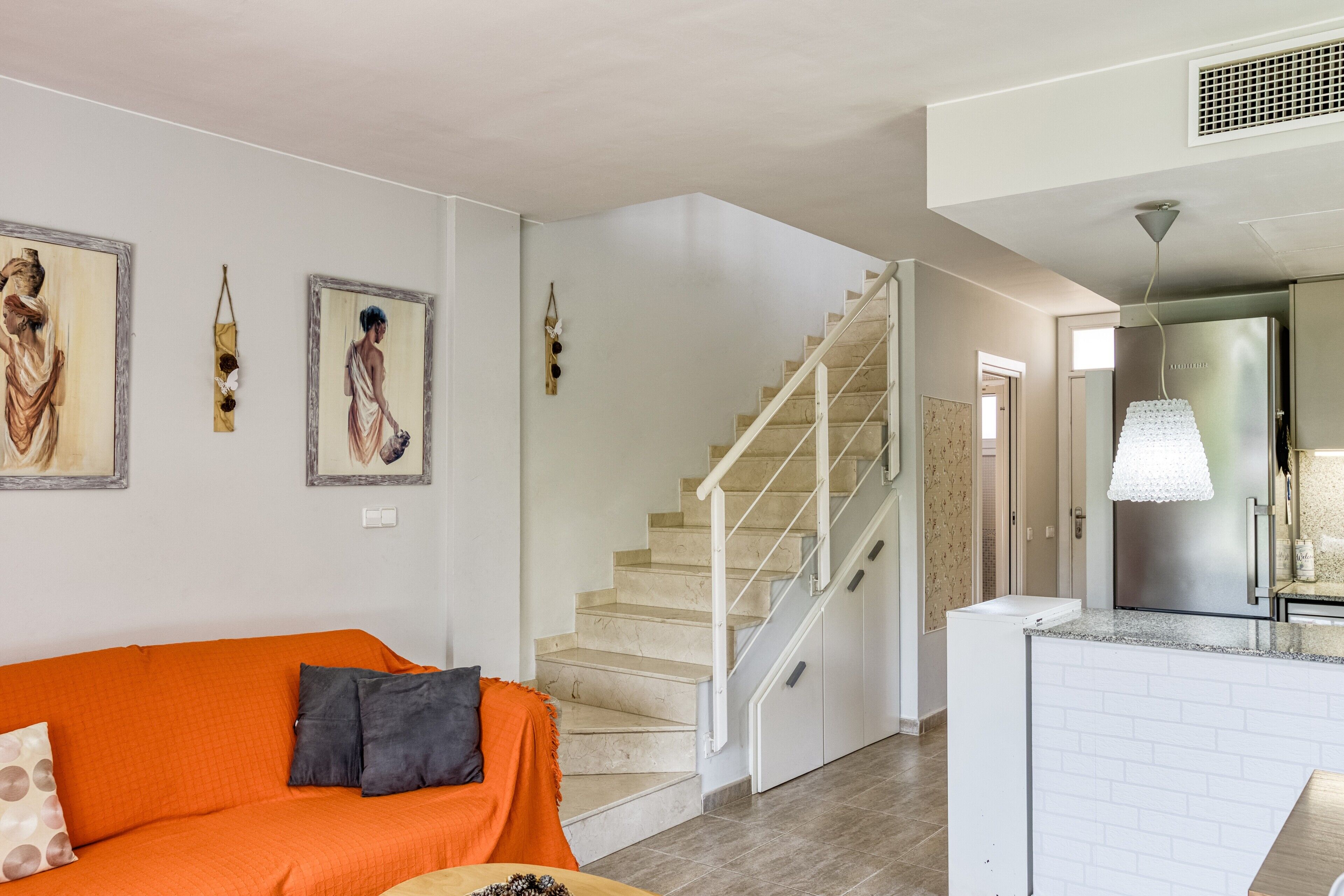 Een moderne woonkamer met een bank, een trap en een keukenhoek.