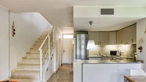 Een moderne keuken met een centraal eiland, roestvrijstalen apparatuur en een trap naar een ander niveau.