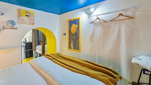 Habitación de hotel con cama, espejo, cuadro, toallero y cortina de ducha.