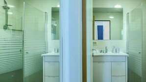 A bathroom with two sinks, a shower, and a mirror.