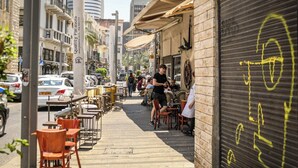 A street with outdoor seating, cars, and buildings.