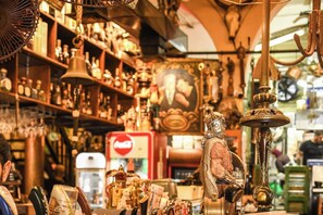Ein überfüllter Antiquitätenladen mit verschiedenen Ausstellungsstücken, darunter eine Glocke, eine Statue und ein Coca-Cola Kühlschrank.